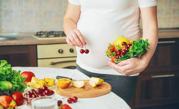 Una mujer embarazada come verduras y frutas. Enfoque selectivo. Comida
. - Foto, imagen