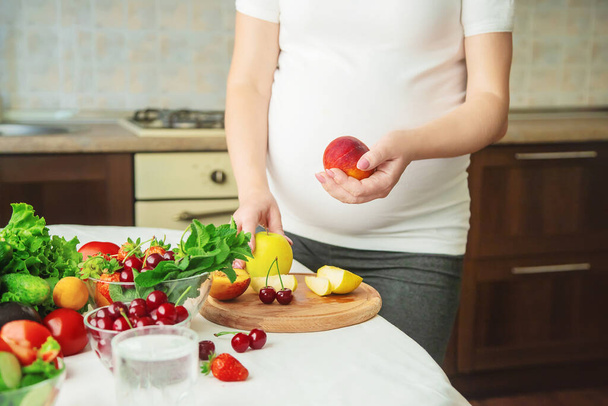 Una donna incinta mangia frutta e verdura. Concentrazione selettiva. Alimenti. - Foto, immagini