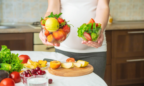 A pregnant woman eats vegetables and fruits. Selective focus. Food. - Foto, Imagen