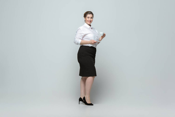 Young caucasian woman in office attire on gray background. Bodypositive female character. plus size businesswoman - Foto, Imagem