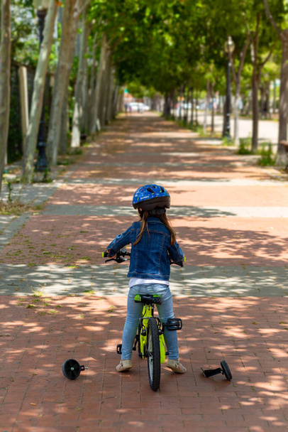 Αφαίρεση των μικρών τροχών από το κίτρινο ποδήλατο ενός μικρού κοριτσιού - Φωτογραφία, εικόνα