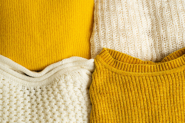 Mucchio di vestiti lavorati a maglia giallo colore bianco. Autunno inverno concetto. Copia spazio - Foto, immagini