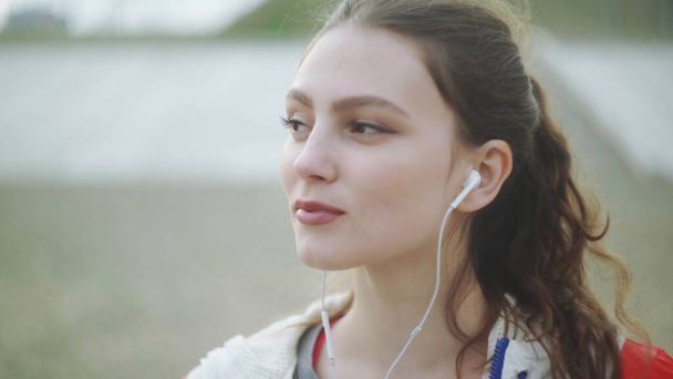 Nahaufnahme einer jungen Frau mit Kopfhörer zur musikalischen Motivation für Ausdauertraining - Foto, Bild