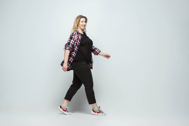 Young caucasian woman in casual wear on gray background. Bodypositive female character, plus size businesswoman - Photo, image