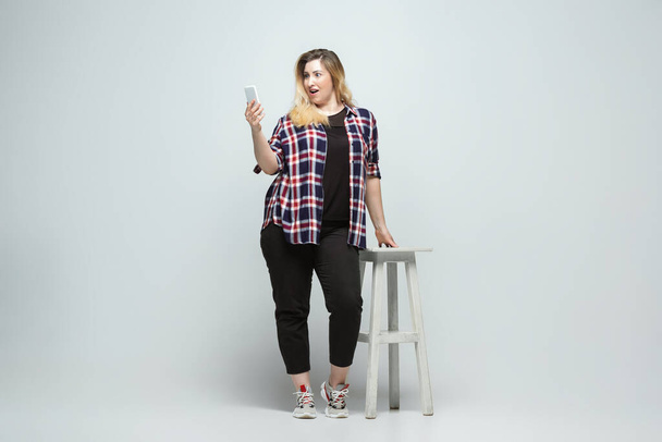 Young caucasian woman in casual wear on gray background. Bodypositive female character, plus size businesswoman - Foto, Imagem