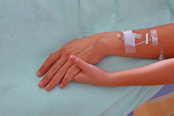 Bras du patient avec kit de perfusion en plastique et main d'enfant tenant un patient - Photo, image