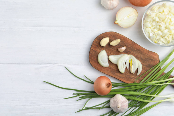 Flat lay composition with cut onion and garlic on white wooden table. Space for text - Foto, afbeelding