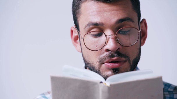 nerd dans des lunettes et chemise à carreaux lecture livre isolé sur blanc - Séquence, vidéo