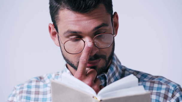 nerd dans des lunettes et chemise à carreaux lecture livre isolé sur blanc - Séquence, vidéo