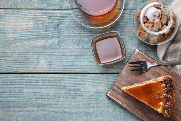 Piece of delicious cake with caramel served on blue wooden table, flat lay. Space for text - Foto, immagini