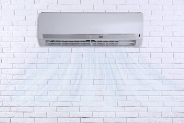 Modern air conditioner on white brick wall indoors - Zdjęcie, obraz