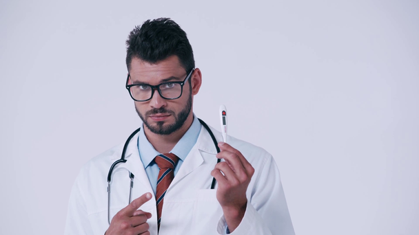 médico serio apuntando al termómetro aislado en blanco
 - Imágenes, Vídeo