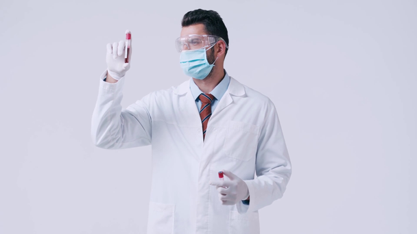 médico con máscara médica que mira los tubos de ensayo con sangre aislada en blanco
 - Imágenes, Vídeo