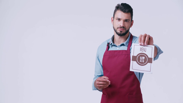 handsome waiter in apron showing menu isolated on white - Footage, Video