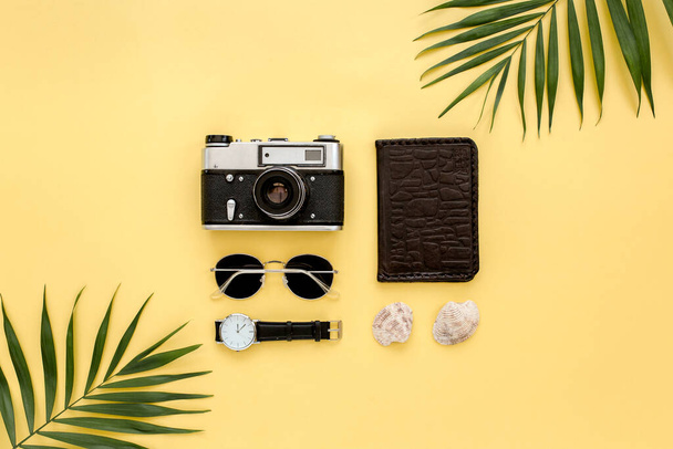 Traveler accessories on yellow background with palm leaf, camera and sunglasses. Flat lay, top view.  - Foto, imagen