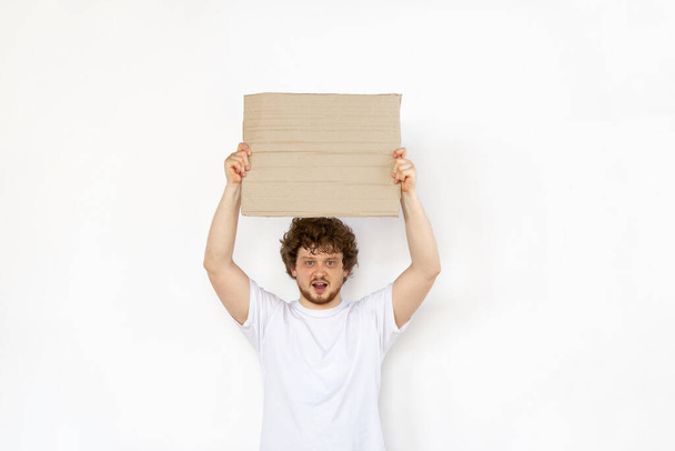 Young man protesting with blank board, sign isolated on white studio background - 写真・画像