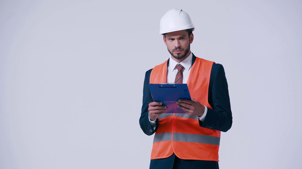 serious architect with clipboard in safety vest and helmet isolated on white - Footage, Video