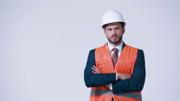 serious architect with crossed arms in safety vest and helmet isolated on white - Footage, Video