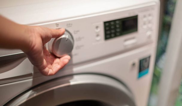 Kobieca dłoń otwierająca pralkę i miejsce na płyn do prania detergentów przygotowujący ubrania, do hygienki i czyszczenia. - Zdjęcie, obraz