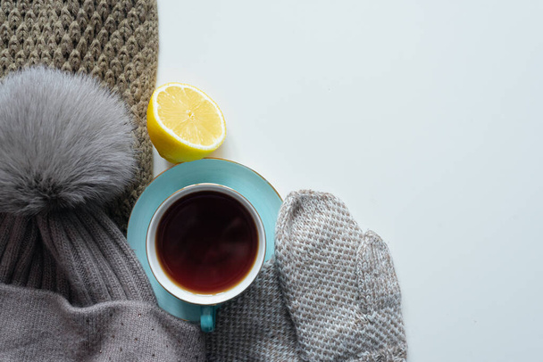 Cup of hot tea, lemon and warm clothes on gray flat lay background with copy space. - Foto, Imagen