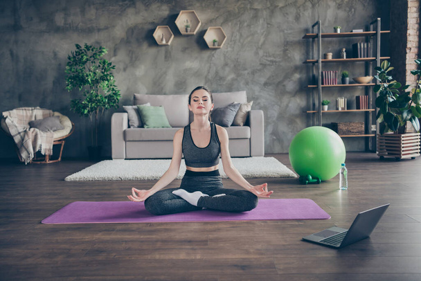 Full size photo of calm focused athlete girl sit floor mat legs lotus position meditate show om symbol wear panties in house indoors - Photo, Image