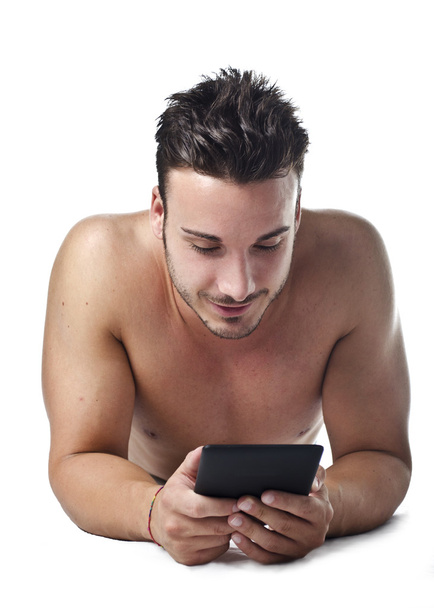 Handsome young man shirtless reading ebook on the floor - 写真・画像