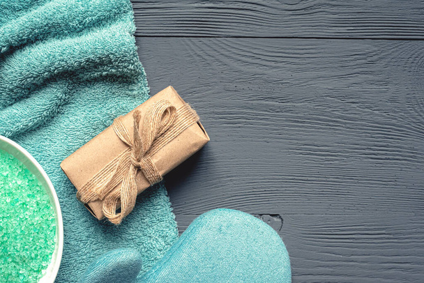 Bath salt, wash glove, towel and craft soap in paper package on gray background. Hygiene abstract background. - 写真・画像