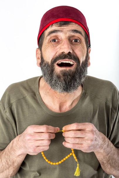 Menschliche Mimik und Körpersprache. Porträt eines zweifelnden alten muslimischen Mannes in Brille, der seinen grauen Bart reibt und Zweifel äußert und zögert, eine Entscheidung zu treffen. Rosenkranz mit bärtiger männlicher Hand. - Foto, Bild
