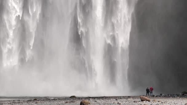 mężczyzna i kobieta para ogląda wodospad Skogafoss w Islandii - Materiał filmowy, wideo