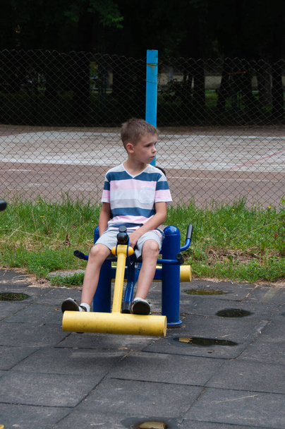 Menino entra para esportes no verão lá fora no playground está envolvido no simulador
 - Foto, Imagem