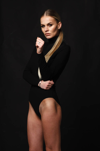 divat és fehérnemű koncepció - gyönyörű szőke hölgy portré szexi fekete garbó test fűző sötét háttérrel. Nő visel fehérnemű pózol stúdió fény - Fotó, kép
