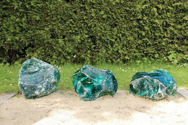 Grote glazen kristallen liggen op het gras. Voorbeelden van ruw glas met scherpe randen. - Foto, afbeelding
