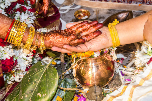 Οι όρκοι ανταλλάσσονταν μεταξύ της νύφης και των γαμπρού με τα χέρια πάνω σε ένα άλλο, ένα σημαντικό έθιμο για μια ινδική γαμήλια τελετή.. - Φωτογραφία, εικόνα