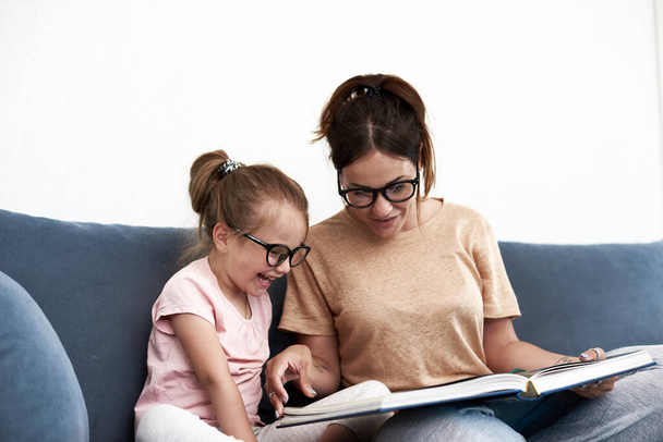 Мати та донька читають книжку. Мати вчить маленьку дівчинку
. - Фото, зображення