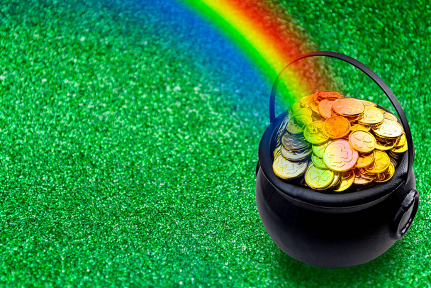 Saint Patrick's Day and Leprechaun's pot of gold coins concept with a rainbow indicating where the leprechaun hid treasure on green with copy space. St Patrick is the patron saint of Ireland - Photo, Image