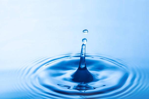 Падіння краплі води впливає на поверхню води. викликає кільця на поверхні води
. - Фото, зображення