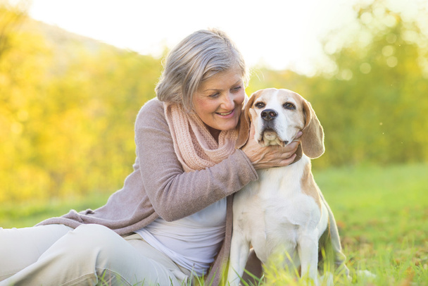 Active senior woman hugs dog - Фото, изображение
