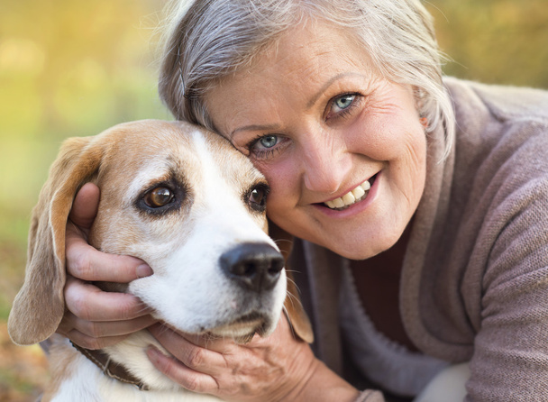Active senior woman hugs dog - 写真・画像