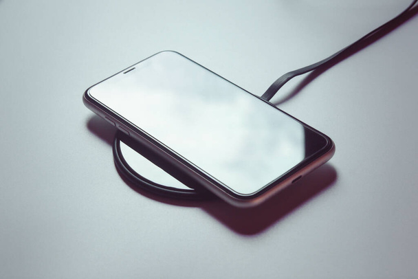 Smartphone charging on a wireless charger  - Valokuva, kuva