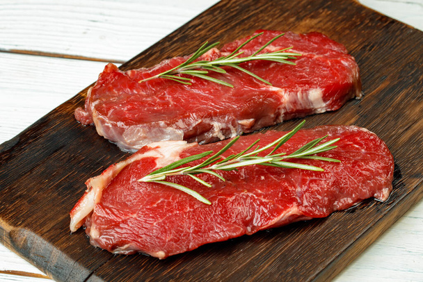 Barbecue veal steaks with rosemary on wooden board - Photo, image