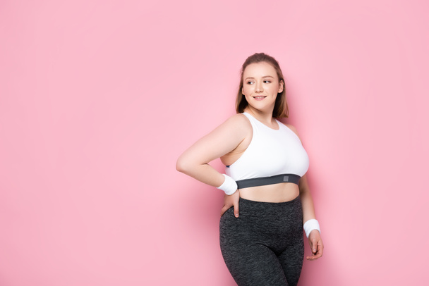 pretty, smiling overweight girl standing with hand on hip on pink - Fotografie, Obrázek