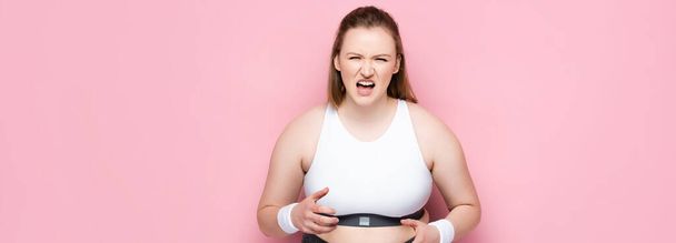 horizontální obraz naštvaný nadváha dívka ve sportovním oblečení křičí na růžové - Fotografie, Obrázek
