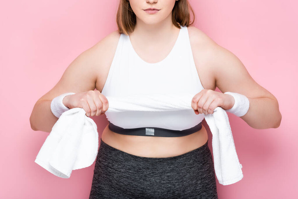 cropped view of overweight girl in sportswear holding white towel on pink - Photo, Image