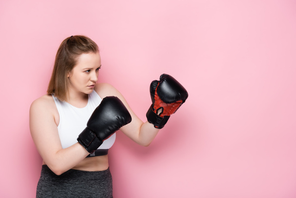 attentive size plus girl training in boxing gloves on pink - Foto, imagen