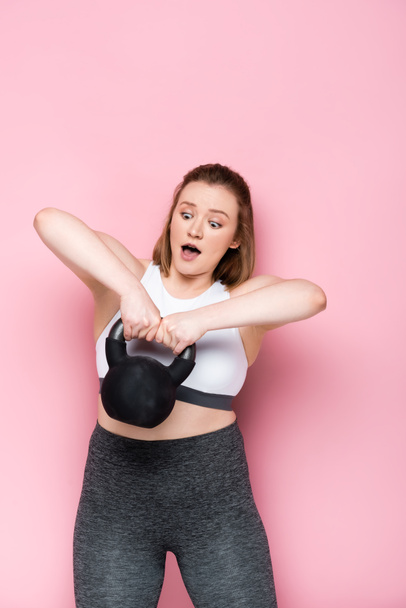shocked overweight girl ligfting heavy weight on pink - Photo, Image