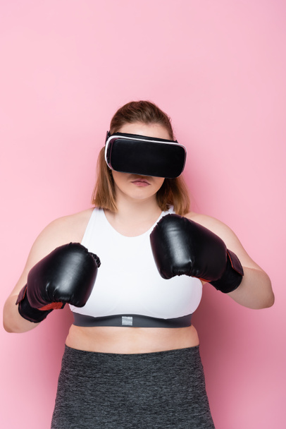 μέγεθος συν κορίτσι σε αθλητικά ρούχα, ακουστικά VR και γάντια πυγμαχίας σε ροζ - Φωτογραφία, εικόνα