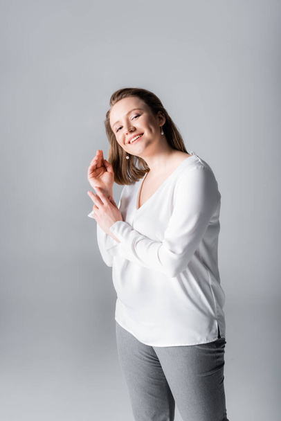 happy, elegant overweight girl smiling at camera while posing isolated on grey - Fotografie, Obrázek