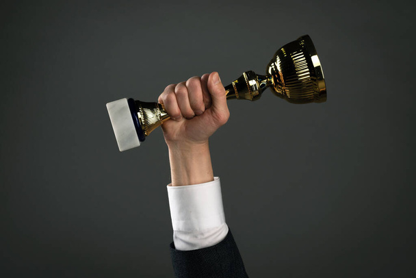 Businessman with a golden cup award trophy in hand. First place concept background. Best worker award. Business achievement. - Photo, Image