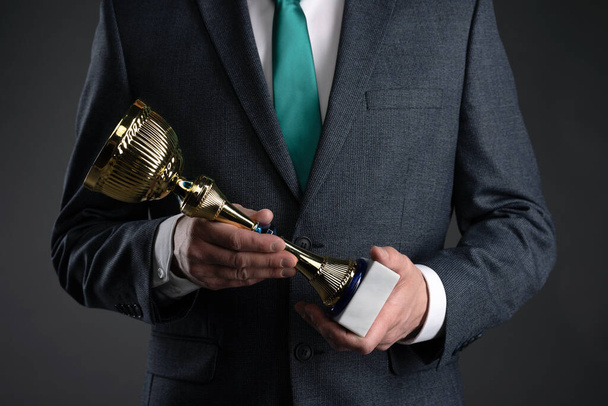 Businessman with a golden cup award trophy in hand. First place concept background. Best worker award. Business achievement. - Фото, зображення