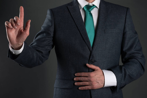 Businessman is showing his index finger up on a gray background. Attention please. Business statement. - Fotoğraf, Görsel